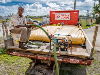 Mercy corps volunteer sitting on water truck in the bahamas after hurricane dorian.