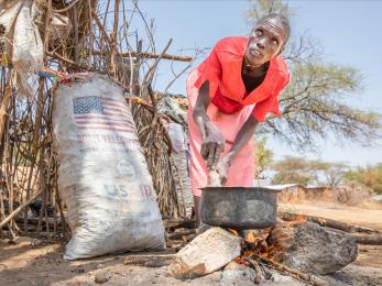 Kenyan woman cooking outside.