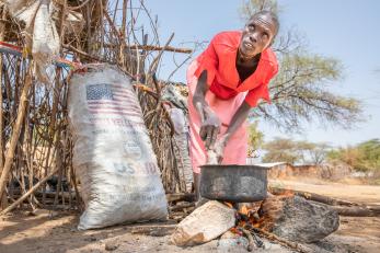 Kenyan woman cooking outside.