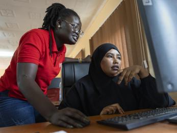 Two kenyan women work in front of a computer together.