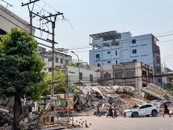 Urban scene, with destroyed building in background.