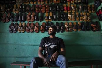A person sitting in front of a wall of footwear.