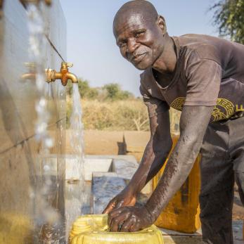 A person filling a jerry can with water.