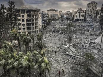 Residents walk through the rubble of the al-remal neighborhood in gaza city after it was destroyed by air raids. © eyad baba for mercy corps