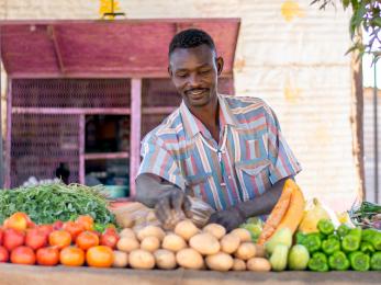 Sudanese man working in vegetable stall.