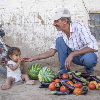 Syrian granddaughter and grandfather eating watermelon