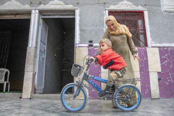 A parent helping their child to ride a bicycle.