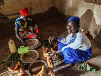 Two people feeding chickens.
