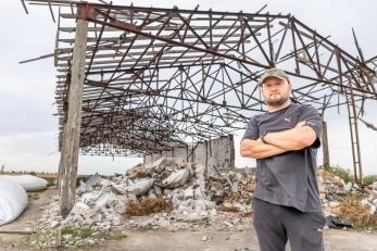 An agricultural worker in front of their ruined grain warehouse.