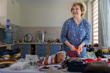 A person making traditional ukrainian dolls and clothing in their home.