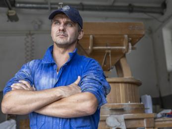 Ukrainian man stands in workspace with arms crossed.