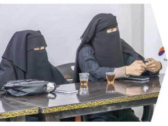 Two syrian woman site at a table in a meeting atmosphere.